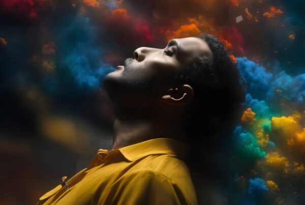 A man in a yellow shirt with colorful clouds around him, suggesting serene contemplation.