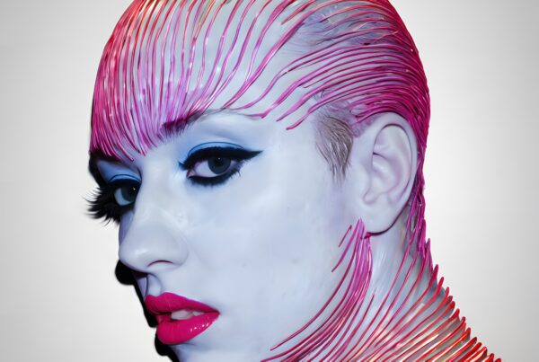 A futuristic portrait with bold makeup and intricate, linear headpiece design.