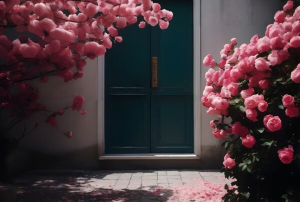 A blue door surrounded by abundant pink blossoms creates a serene garden entrance.