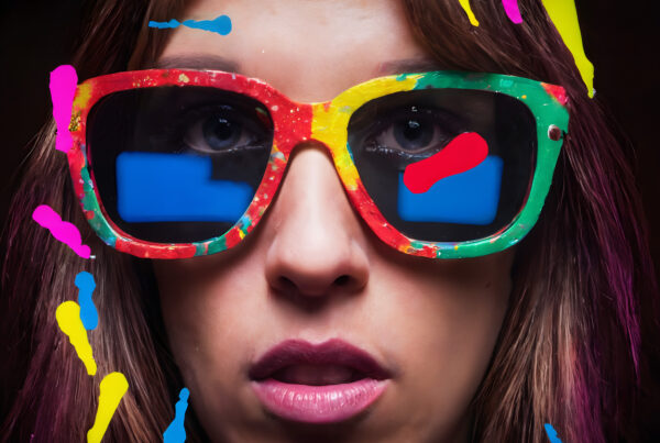 A close-up photo of a person wearing large, colorful sunglasses.