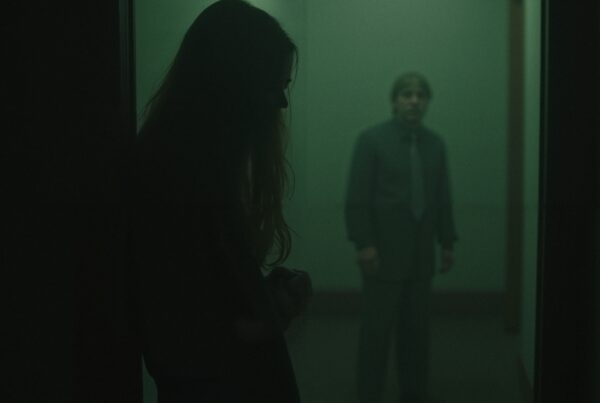 Mysterious scene in dark hallway, with silhouetted woman and man.