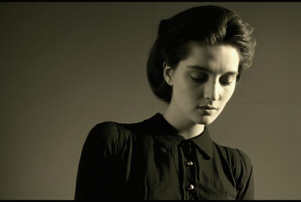 Vintage-inspired portrait of a contemplative young woman wearing a dark blouse with a serene expression.