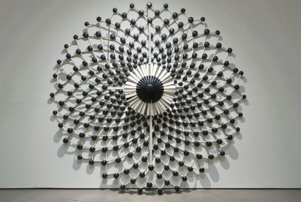 Architectural wall sculpture with black spheres and geometric pattern.