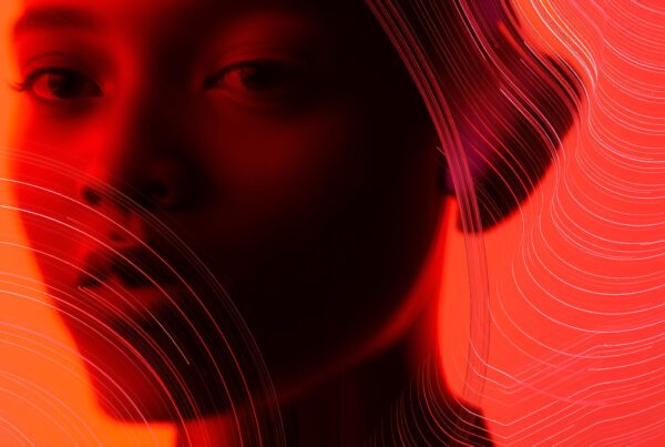A woman's face in red shadow with abstract lines.