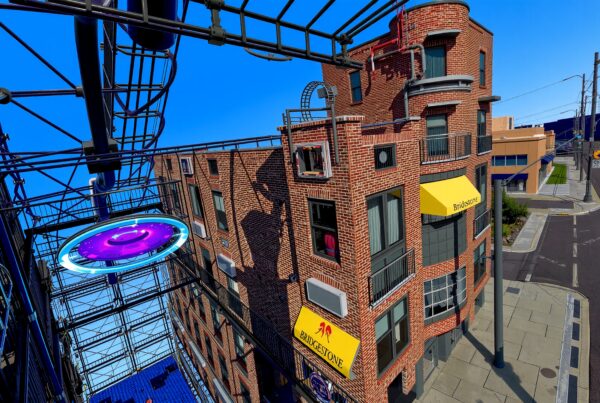 A brick building with a futuristic structure under a bright blue sky in a cityscape.