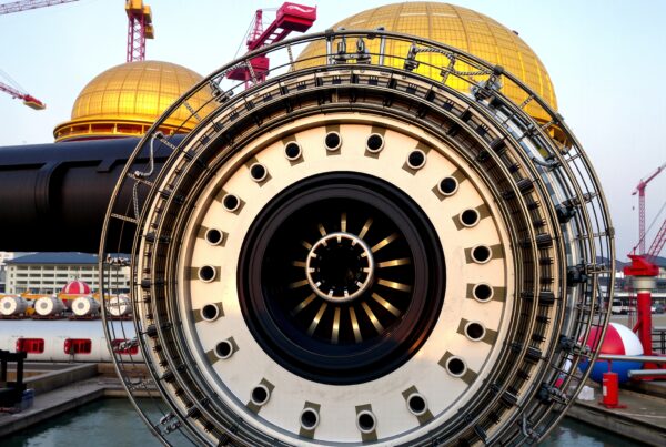A large industrial wheel with cranes and gold domes on a construction site.