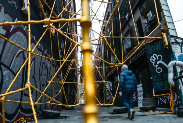 Golden scaffolding in urban graffiti alley with pedestrian.