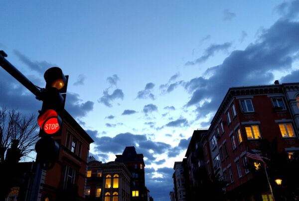 Urban street scene at dusk with traffic light and cloudy sky.