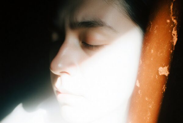 A serene close-up portrait with dramatic light and shadow contrasts.