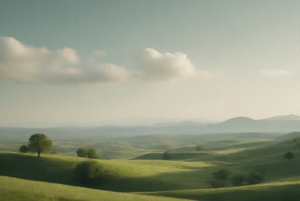 Serene landscape with rolling green hills, distant mountains, and a tranquil sky.