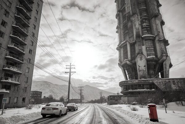 A snowy urban scene features a towering structure and snowy road.