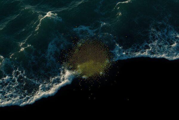 Aerial view of ocean waves over dark water with floating golden dots creating an abstract effect.