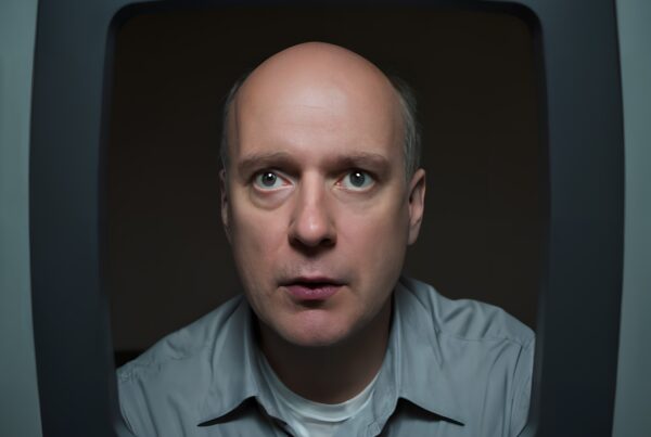 Image of a man framed within an old-fashioned TV screen, evoking vintage nostalgia through his introspective gaze.