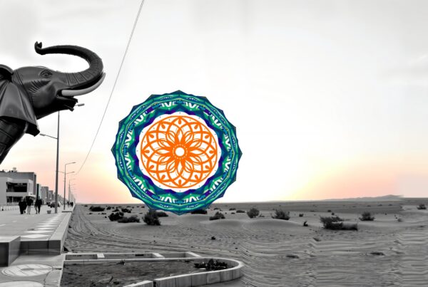 A metallic elephant sculpture alongside a colorful mandala design in a desert sunset.