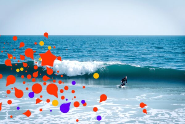 Surfer rides wave with colorful abstract design.