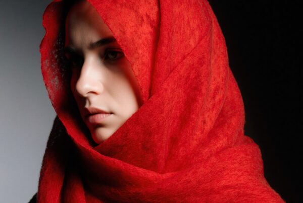 A thoughtful portrait of a woman wrapped in a red scarf.