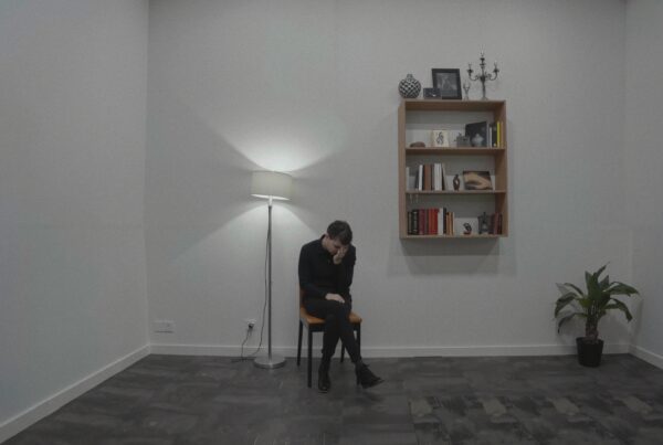 A person sits alone in a minimalist room, conveying solitude.