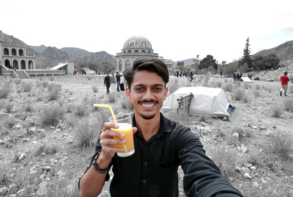 Man smiling with juice at historical site.