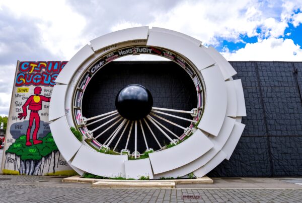 Circular urban art installation resembling an eye with graffiti and plants.