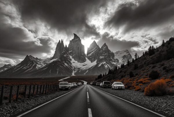 Dramatic mountain range under cloudy sky with road.