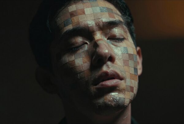 Close-up of a man with multicolored mosaic squares on his face creating an artistic and introspective visual effect.