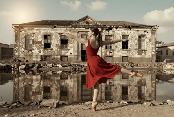 Ballerina dancing gracefully near ruined building reflected in dirty water