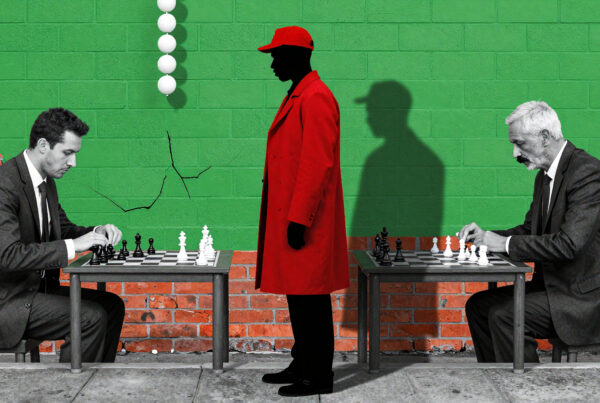 Two businessmen playing chess outdoors with mysterious red-coated figure watching silently