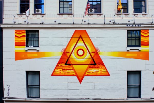 Vibrant eye-in-triangle mural on urban building facade blending artistry with cityscape