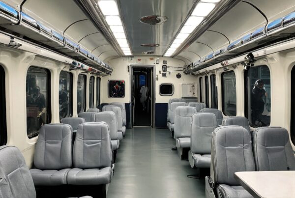 Modern train interior with gray seats and large windows.