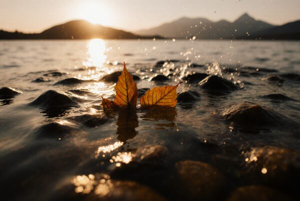 A serene sunset over a lake with autumn leaves in the foreground.