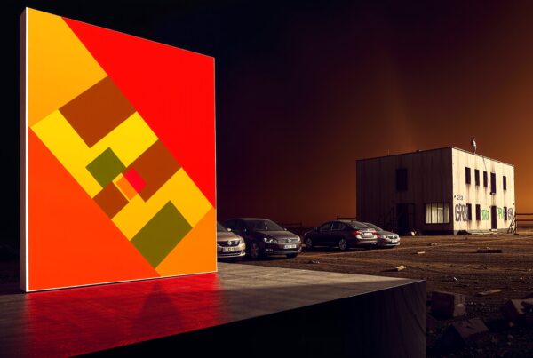 A vibrant geometric painting contrasting against an urban landscape at sunset.