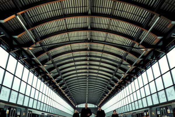 People walking through spacious modern railway station under high vaulted ceilings with natural lighting