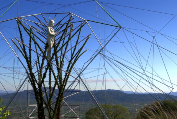 A geometrically intricate sculpture blending with nature under a clear sky.