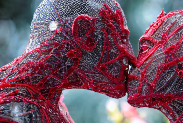Abstract humanoid figures decorated with intricate red threads in an artistic embrace.