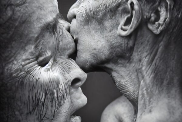 Grayscale depiction of two individuals in a poignant, intimate kiss, emphasizing texture and emotion.