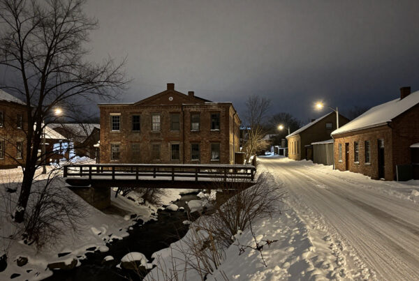 Snowy winter night bridge over creek in old brick town