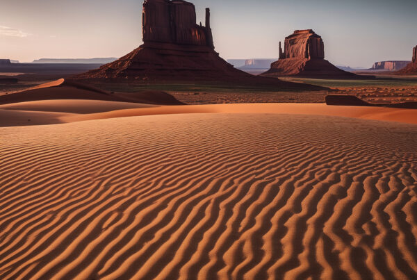 Desert landscape with sand dunes and red rock buttes under clear sky
