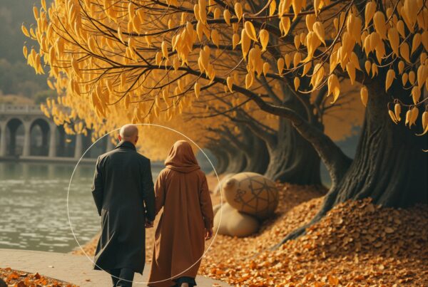 A couple strolls under golden trees along a tranquil autumn path by the water.