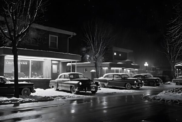 A snowy, vintage street at night with classic cars parked, illuminated by cozy shopfronts and gentle streetlights.