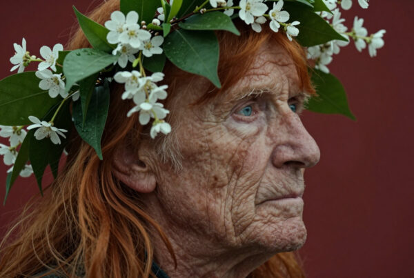 Elderly woman wearing floral crown looking pensively into distance