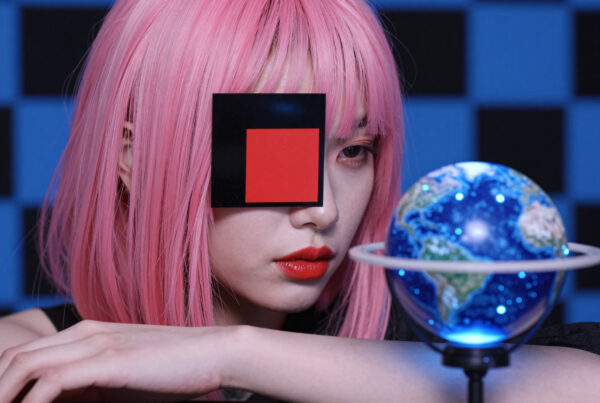 Woman with pink wig holding glowing Earth globe in futuristic blue room