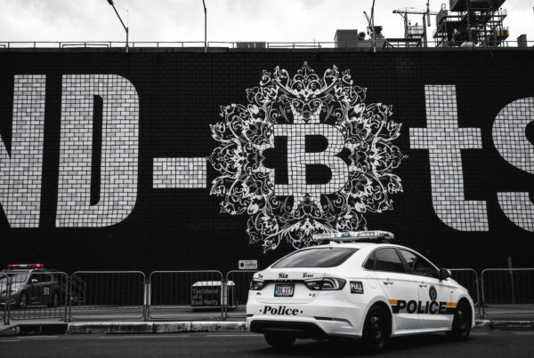 A police car in front of a mural-covered brick wall in an urban setting.