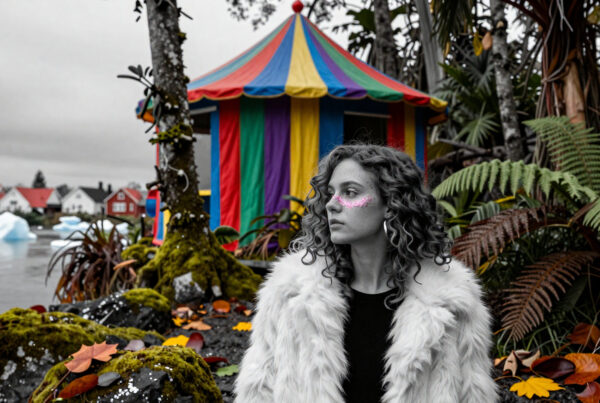 Woman in furry coat with glitter cheeks standing beside colorful circus tent surrounded by ferns and icebergs