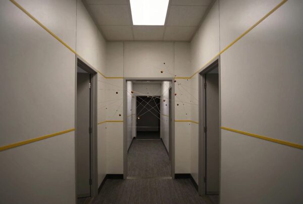 A minimalist hallway with geometric art installation of spheres and wires.