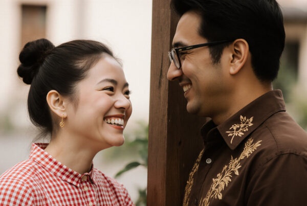 Happy smiling Asian couple laughing together outdoors near wooden fence