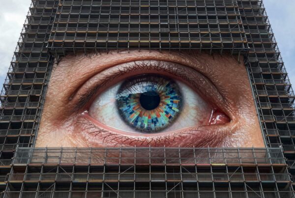 A massive eye art installation on a building facade surrounded by scaffolding.