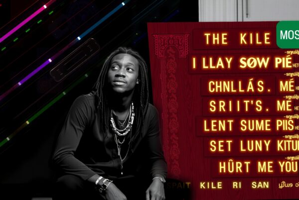 A stylish man with dreadlocks looks contemplative under colorful neon lights beside an illuminated board.