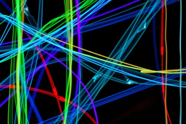 An abstract display of intersecting multicolored light trails against a black background.