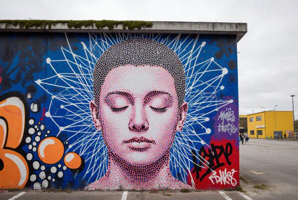 Street art mural featuring a serene face with geometric patterns and abstract graffiti on a blue background.