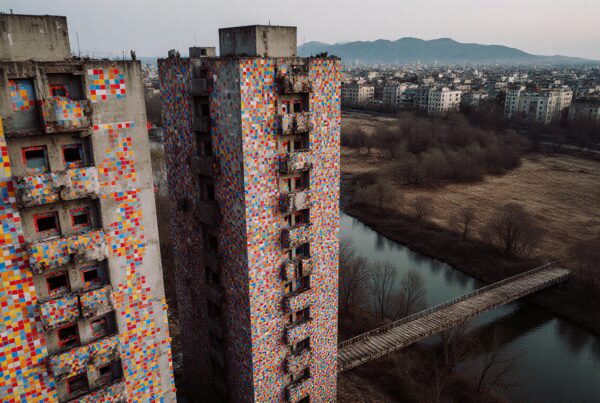 Aerial view of colorful towers with vibrant tiles beside a river and urban landscape.